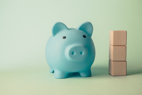 Piggy bank and wooden blocks on green background. Saving money concept.