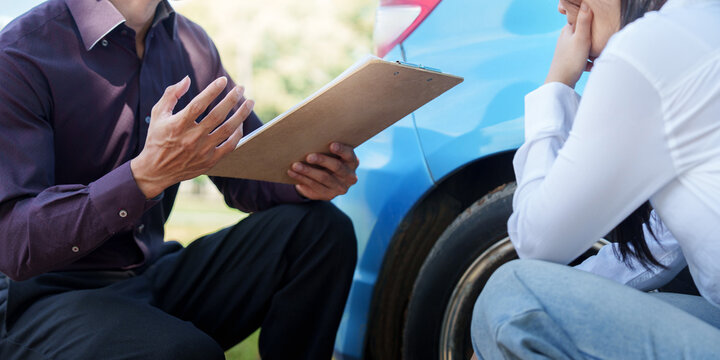 Auto insurance agent evaluating car damage with clipboard for claim service