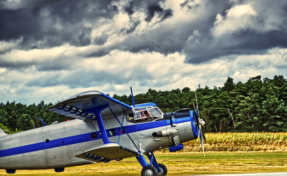 Vintage biplane on an airfield preparing for takeoff under dramatic stormy sky, showcasing classic aviation history and travel