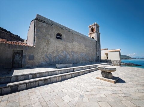 Historic Church of Saint Orsola with crenellated bell tower and stone fountain terrace overlooking the sea in Cefal&ugrave;, Sicily, Italy.