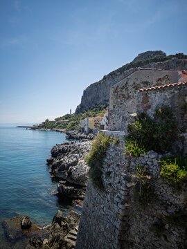 Historic stone bastion sea wall along the rocky coastline leading to La Rocca cliff in Cefal&ugrave;, Sicily, Italy.