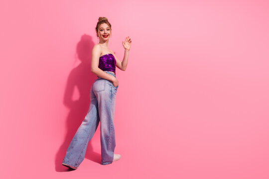 Young stylish woman in casual fashionable outfit standing against pink background, expressing charm and happiness