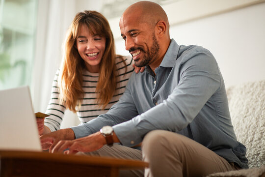 Couple making online purchase with laptop and credit card at home