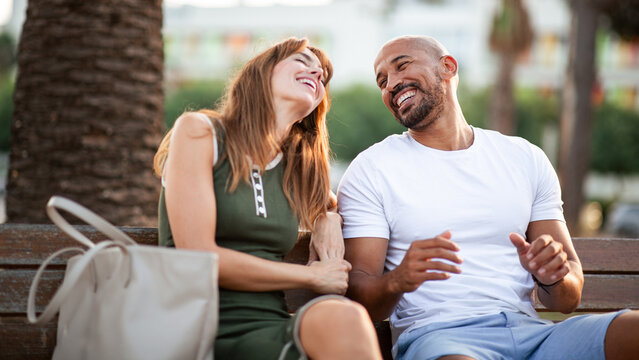 Laughing couple sharing joyful moment on outdoor bench