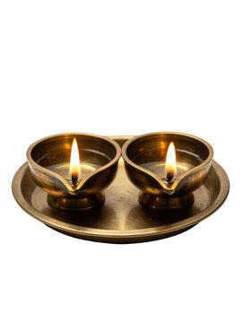 Two lit brass diyas on a round brass plate, isolated on transparent background