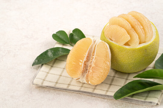 Fresh pomelo fruit with leaf on white table background.