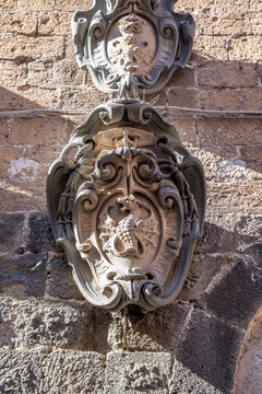 Heraldic relief on Torre del Moro featuring an hydra or dragon below a coat of arms surmounted by a papal tiara and crossed keys, recalling Orvieto's medieval history, Orvieto, Umbria, Italy