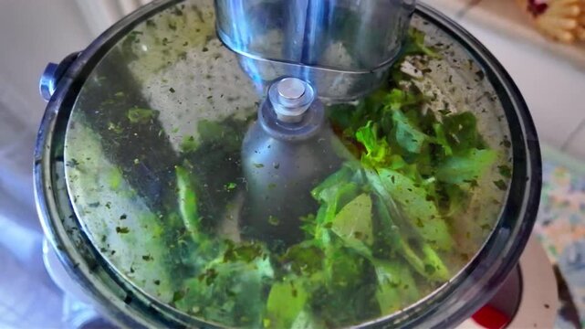 4K footage of a blender grinding basil and pine nuts in slow motion to make Genoese pesto for a Mediterranean diet. Ideal for cooking classes and diet-related content.