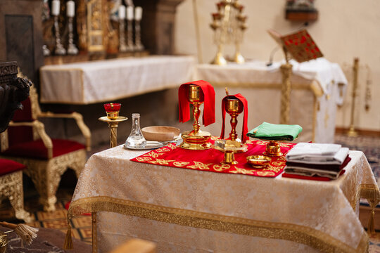 Altar with gold chalices and liturgical vessels on a red embroidered cloth prepared for communion and eucharist service