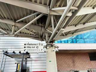 Obraz premium Platform signage and canopy structure at a modern urban train station showing way out directions and structural steel pillar with security cameras