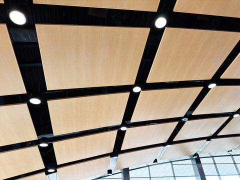 Modern acoustic ceiling panels with recessed lights and exposed black grid in a bright airport terminal interior, Rzeszow, Poland