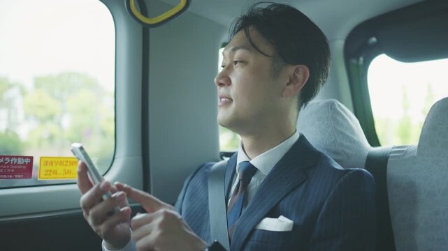 Businessman checking his smartphone screen inside a taxi