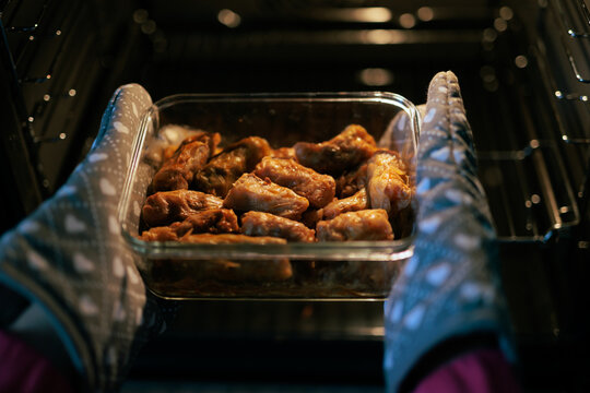 Hands Taking Out Hot Cabbage Rolls From the Oven. Person removes delicious baked meat rolls using colorful protective gloves