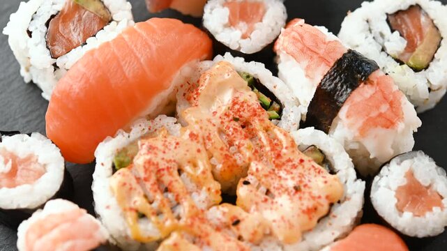 Assorted sushi platter with salmon and tuna nigiri, maki rolls and other Japanese specialties arranged on a serving tray.