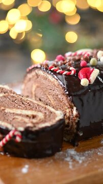 Close-up video of a traditional Christmas yule log cake slowly rotating to showcase its chocolate coating, festive decoration and detailed texture.
