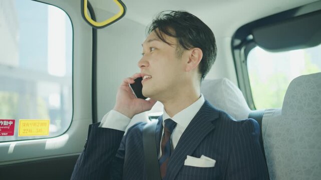 Japanese businessman talking on the phone in the back seat of a taxi