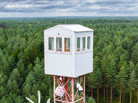 Aerial view of the Lielsalas fire observation tower rising above a dense coniferous forest in Lielsalas, Talsi Municipality, Latvia.