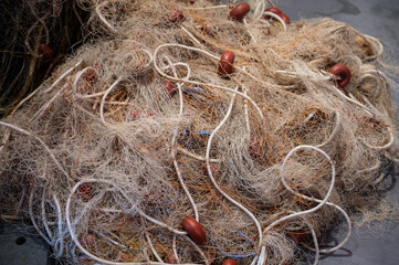Close up of a pile of traditional fishing net with fine white thread, ropes, and plastic floats. © Adolf