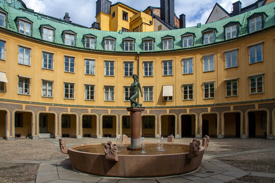 Discover the hidden charm of Gamla Stan. The scenic circular Brantingtorget square in Stockholm, Sweden, featuring a beautiful fountain and striking historic architecture. Perfect for travel media.