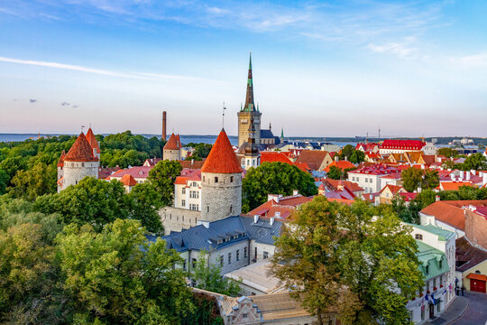 Stunning aerial view of Tallinn old town, Estonia, with Baltic sea background. Featuring medieval fortress towers, red roofs, Saint Olaf church spire, and coastal cityscape for European travel.