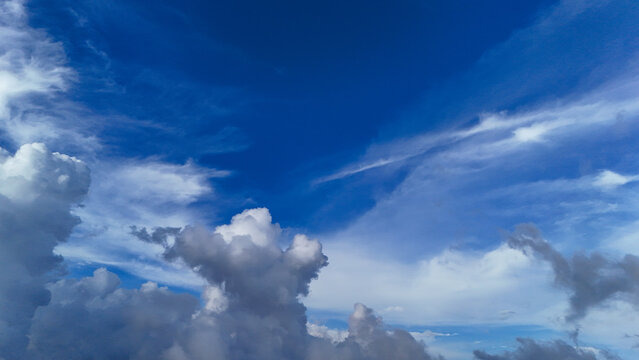Aerial view of fluffy white clouds drifting across a vibrant blue sky over the landscape of Sukabumi Regency, West Java, Indonesia.