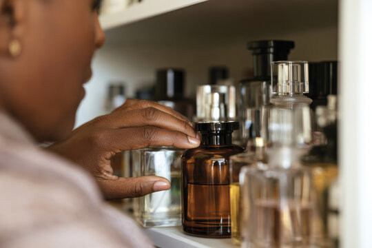 A woman examines exquisite perfume bottles in a curated shelf, signifying the journey of personalizing fragrance choices for deeper emotional connections.