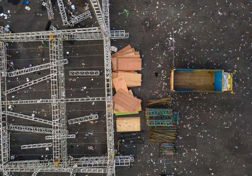 Aerial view of metal scaffolding, stacks of plywood, and a truck on a construction site with debris on the ground in Purwokerto, Central Java, Indonesia.