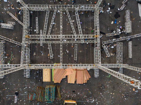 Aerial view of a large metal truss structure for an event setup with wooden planks and scattered construction materials on the ground in Purwokerto, Central Java, Indonesia.