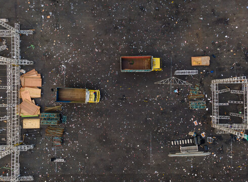 Aerial view of yellow trucks, metal scaffolding, and wooden planks scattered across a construction site in Purwokerto, Central Java, Indonesia.