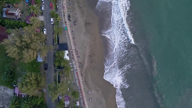 Meulaboh, Indonesia : Top down with rotation motion of aerial drone footage of Meulaboh, coastal city in Aceh of Sumatera, Indonesia showing cars on the road and waves breaks into the beach