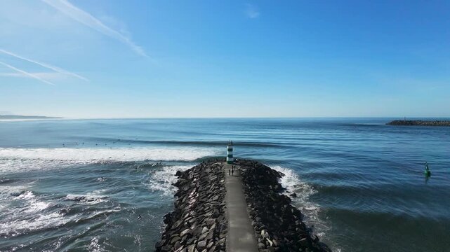 Aerial drone view following the path to a lighthouse in Viana do Castelo, Portugal, with powerful Atlantic waves breaking along the rocky coastline.