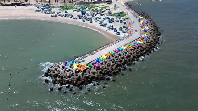 Drone video fly over vibrant colorful concrete wave breakers and sea defense structures with round vietnamese fishing boats along the coastline in Mui Ne, Binh Thuan province, Vietnam.