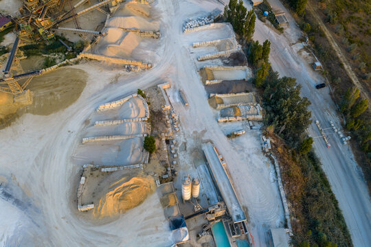 Aerial view of an industrial quarry site featuring piles of gravel, sand, and stone blocks with processing machinery and silos in Rome, Lazio, Italy.