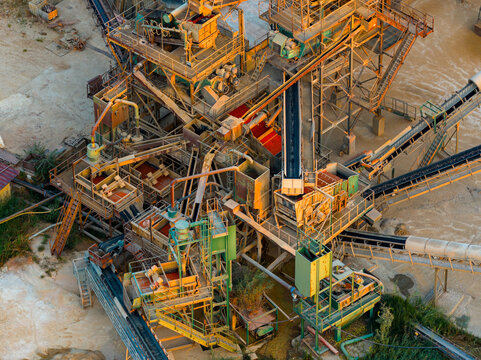 Aerial view of an industrial processing plant with complex conveyor belts, metal machinery, and processing equipment in a quarry setting in Rome, Lazio, Italy.