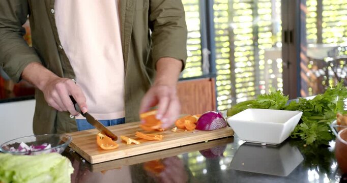 Lifestyle videos indoor of people doing activities at home, chopping orange peppers on board, man pr