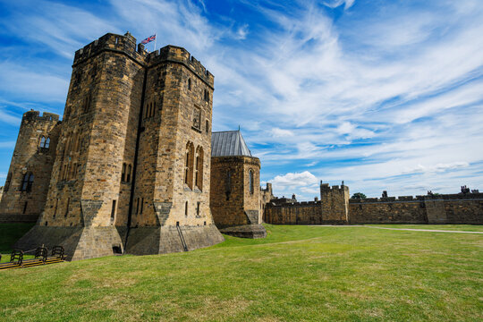 Historic English Alnwick castle with towers on grassy ground, UK