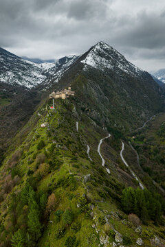 Aerial view of the historic village of Anversa degli Abruzzi perched on a mountain ridge with snow-capped peaks and winding roads in Anversa degli Abruzzi, Abruzzo, Italy.