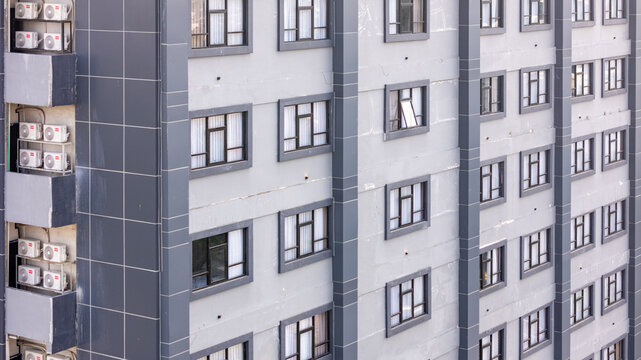 Aerial view of a modern building facade featuring rows of windows and multiple air conditioning units mounted on the exterior in Yogyakarta, Special Region of Yogyakarta, Indonesia.