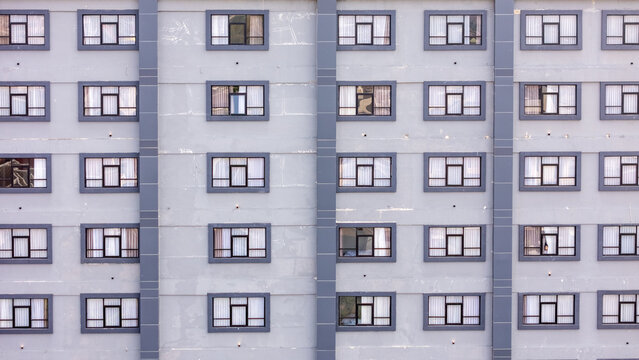Aerial view of a modern building facade featuring rows of uniform windows with white curtains, showcasing architectural symmetry in Yogyakarta, Special Region of Yogyakarta, Indonesia.