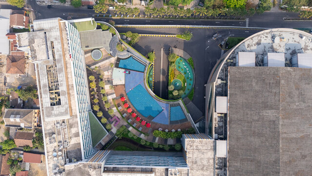 Aerial view of the Marriott hotel featuring a curved swimming pool with red umbrellas and modern architecture in Yogyakarta, Special Region of Yogyakarta, Indonesia.