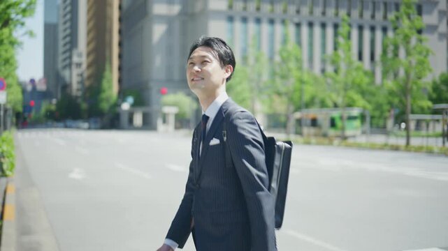 Japanese businessman looking back with a smile at a crosswalk