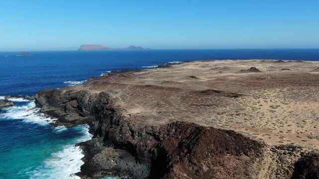 A rear-facing drone shot over Playa de las Conchas, revealing the islets of Monta&ntilde;a Clara and Alegranza in the background on the beautiful Canary Island of La Graciosa.