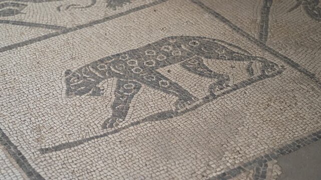 Leopard-shaped tesserae pattern strides across an ancient Roman mosaic panel, detailed in black on pale stone.