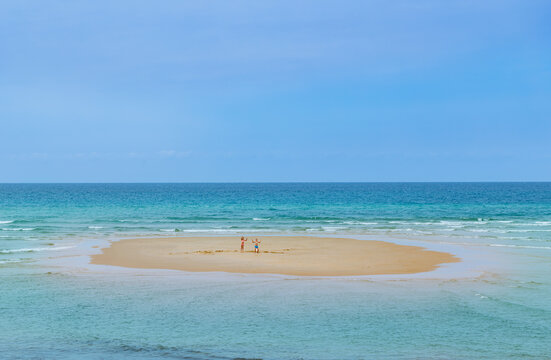 Two kids boy and girl jump, wave on sandy ocean island alone