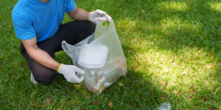 Volunteer collecting plastic trash in park for environmental cleanup