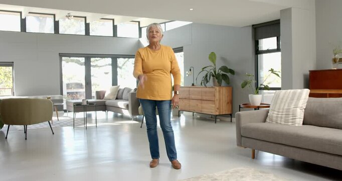 Close up of people talking to the camera, senior woman standing in modern living room, gesturing wit