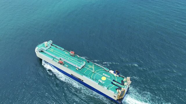 Large roll-on roll-off vehicle carrier ship sailing through the deep blue ocean. Global maritime logistics, international automotive trade, and heavy commercial freight transport