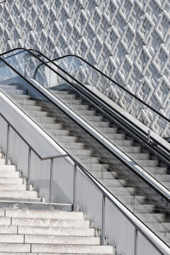 Escalator beside patterned wall and steps creates a clean urban architectural detail emphasizing movement geometry and contemporary design