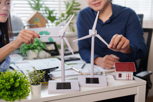 Asian energy consultants discussing wind turbine model for ESG strategy and green building planning