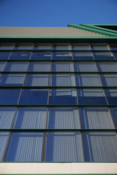 Modern architectural glass building facade against blue sky in low angle view